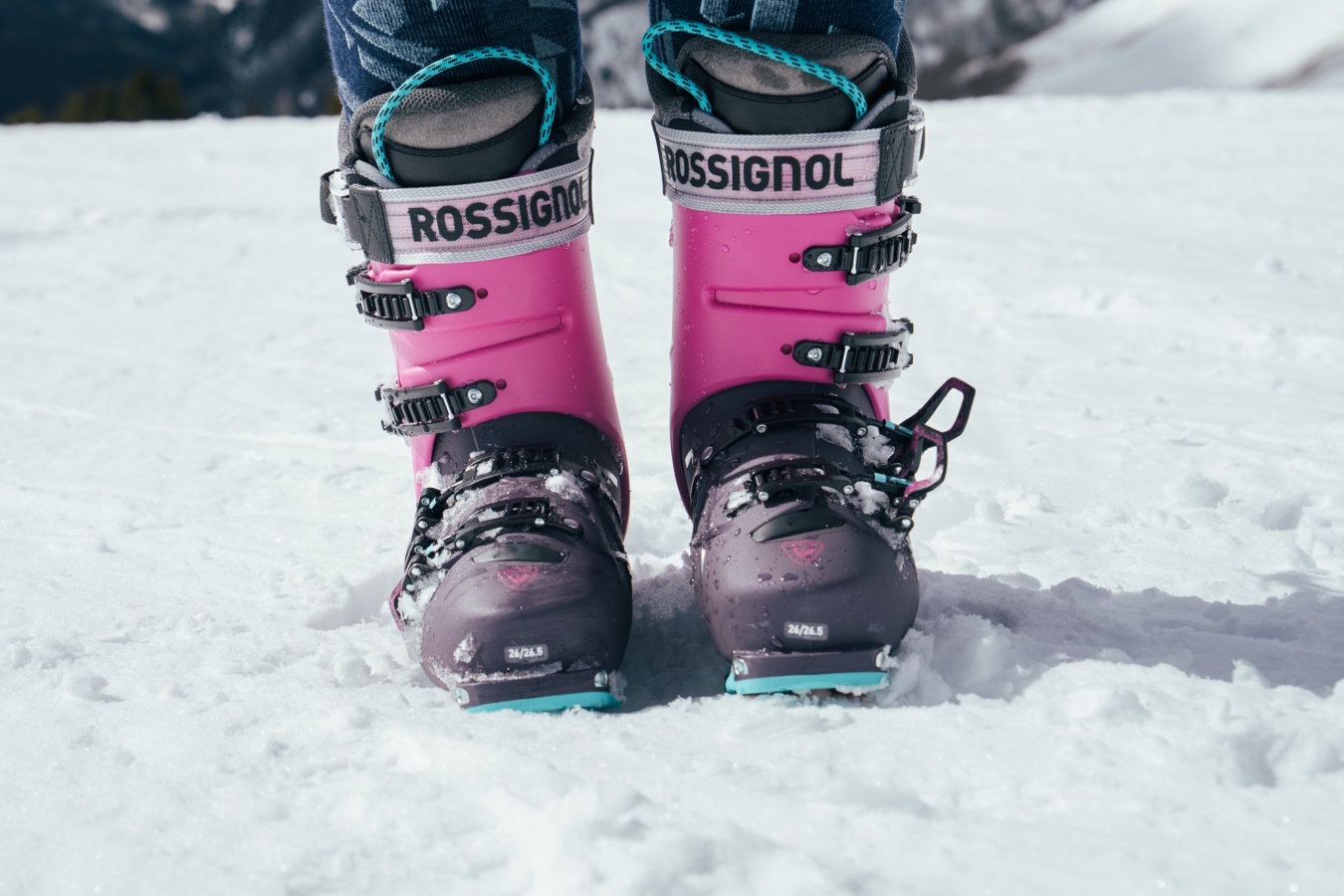 Close-up of pink and black Rossignol Alltrack 130 Elite LV LT ski boots in snow