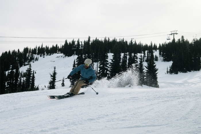 Skier carving turns on Canvas 100 skis at a ski resort