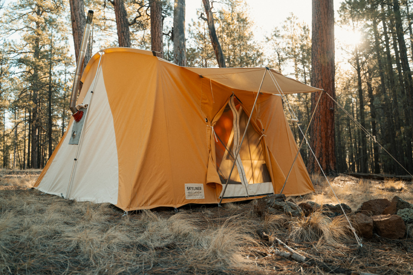 Springbar Skyliner hot tent set up in a wooded campsite with an awning and stove pipe