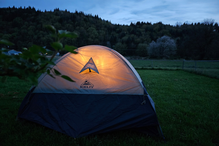 Late Start 4P tent glowing from inside in a grassy campsite at dusk