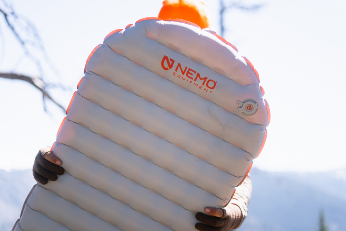 NEMO Tensor sleeping pad held up outdoors with the valve and baffle design visible