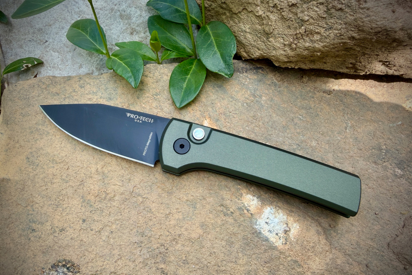 Scapegoat Compact knife shown open on a stone surface with green leaves nearby