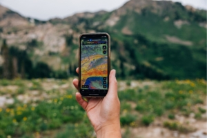 person holds up phone in mountains with a map on it