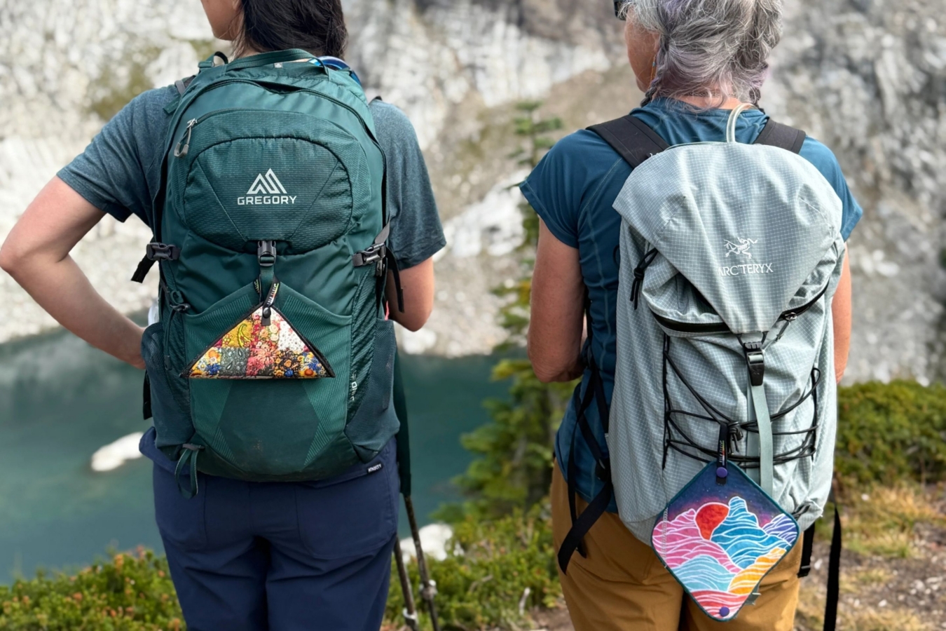 rear view of two women standing on cliff wearing packs