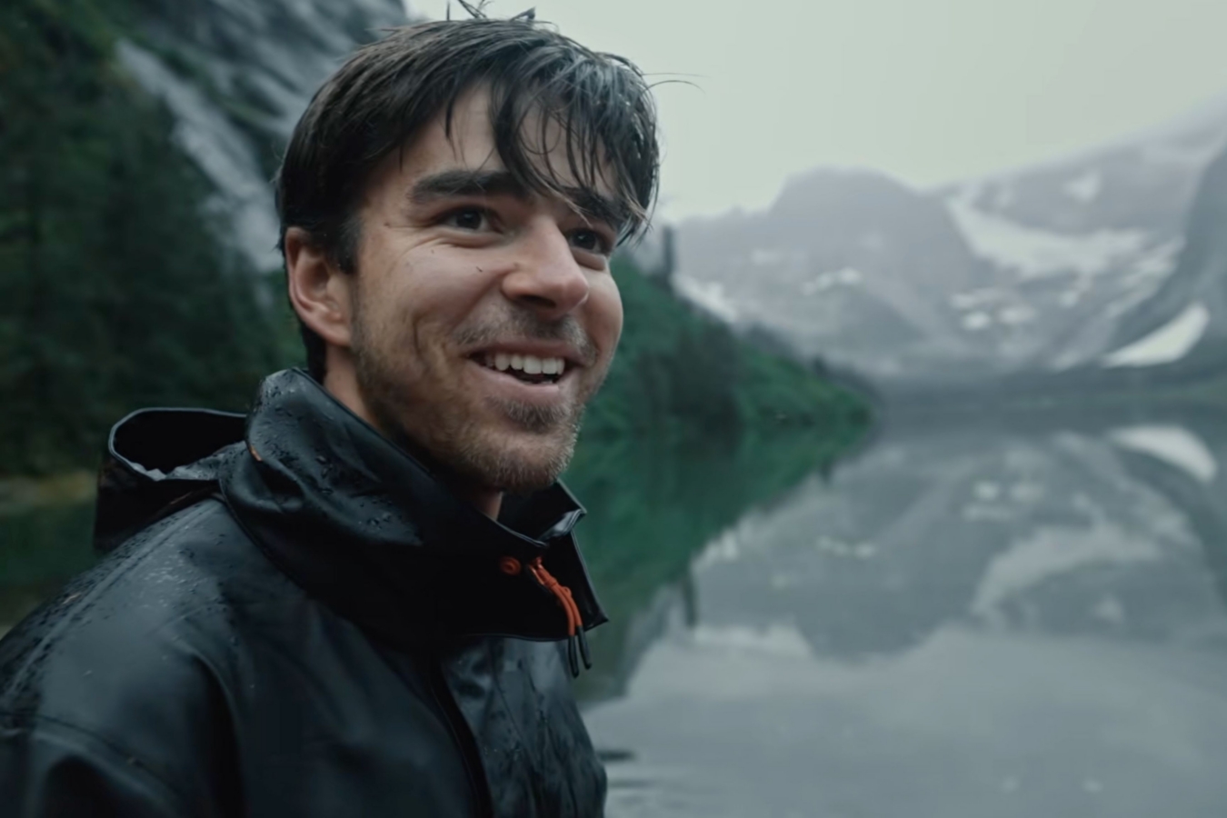 young man stands by lake in nature