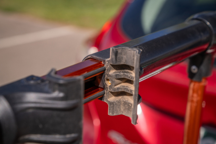 Close-up of a bike rack cradle and arm behind a red car