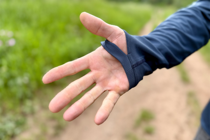 A close-up shows the hoodie thumb loop on one hand