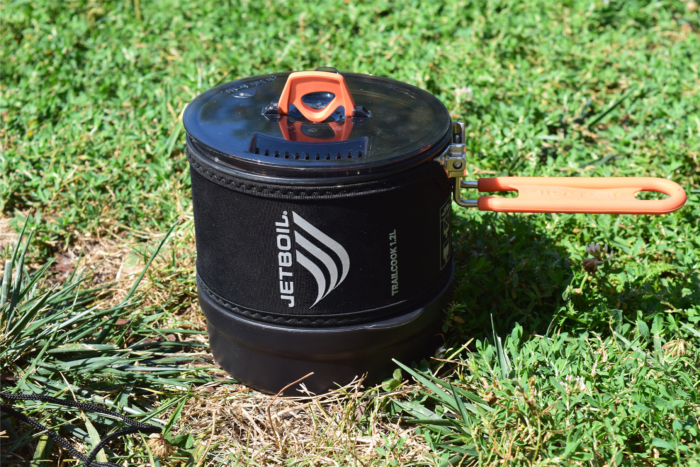 Jetboil TrailCook pot closed with its lid and orange handle extended in the grass