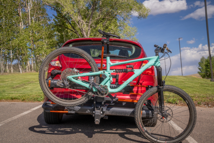 Mountain bike secured on a hitch rack behind a red car