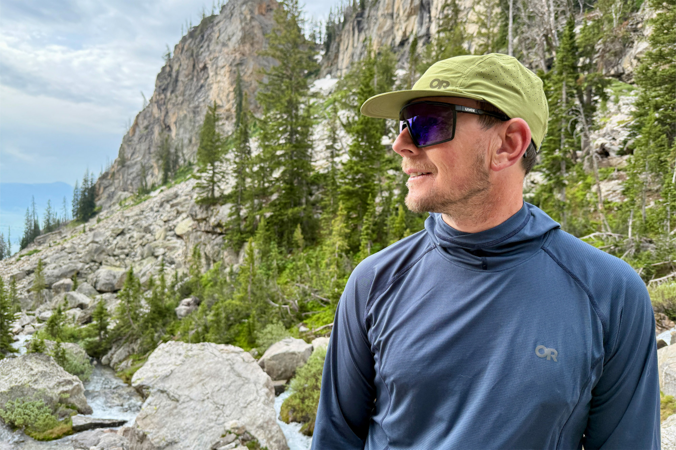 A hiker wears a blue Echo Hoodie on a rocky alpine trail