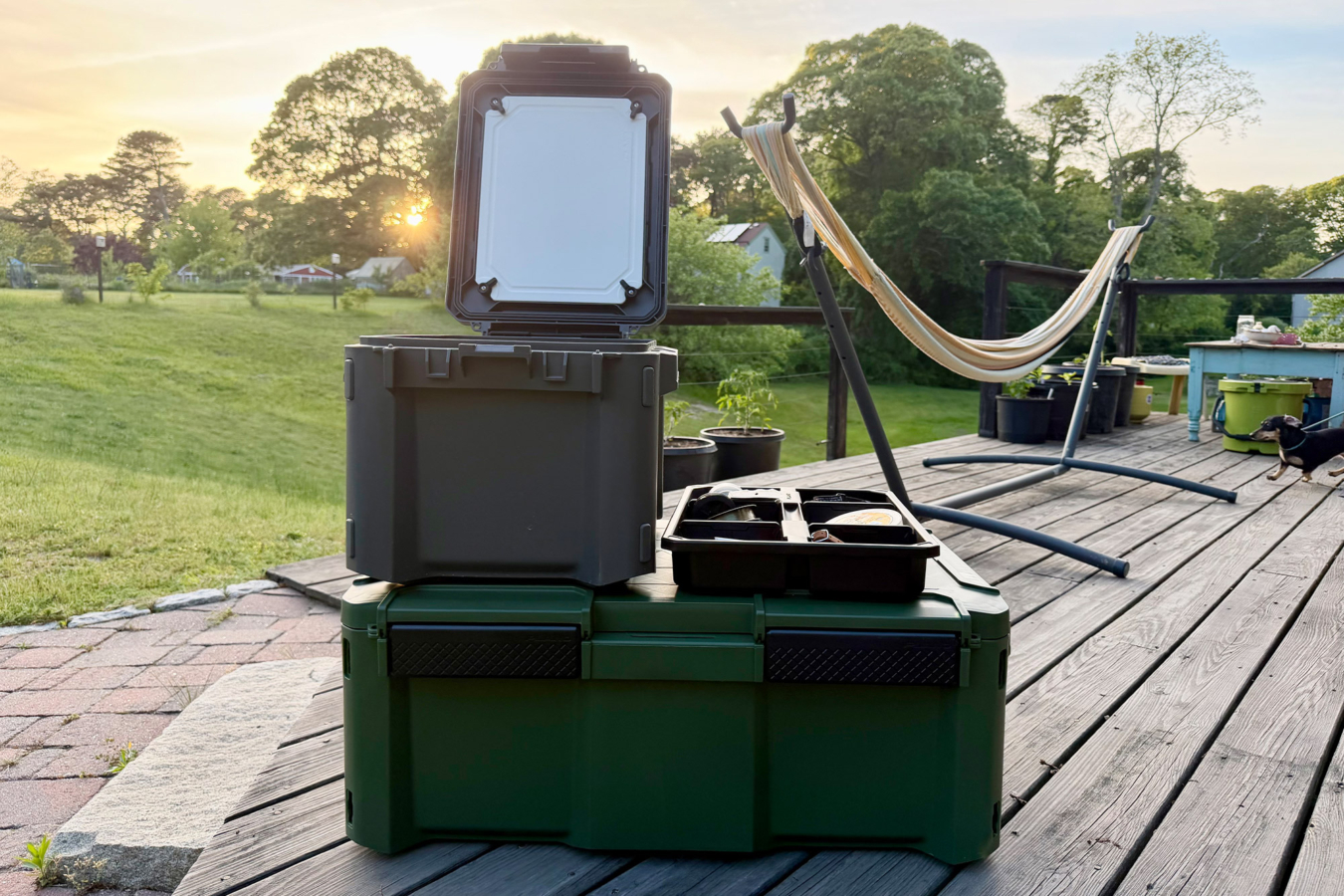 Open storage box with gear tray on a wooden deck at sunset