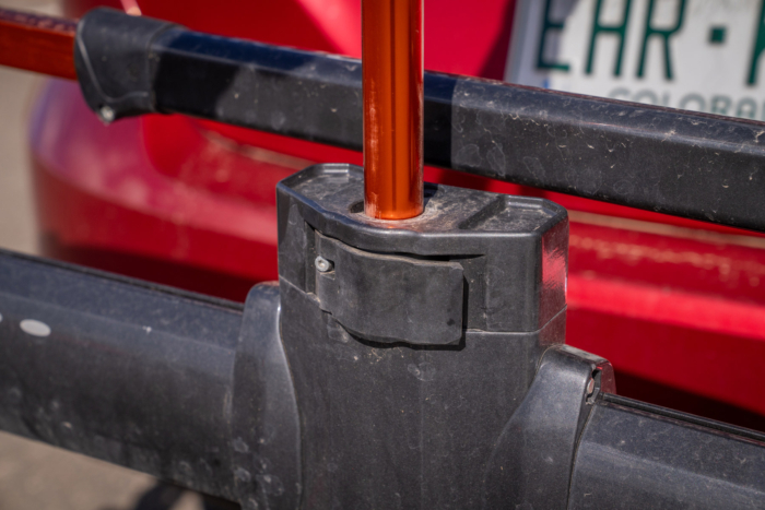 Close-up of the hitch rack repair stand clamp behind a red car