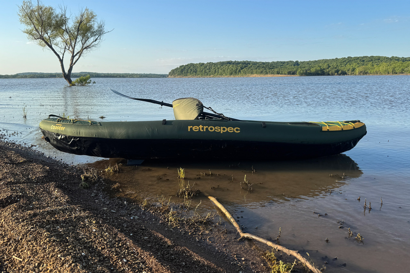 Green Retrospec Coaster kayak resting in shallow water by a lake