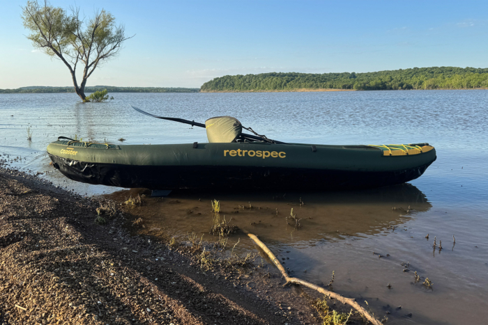 Green Retrospec Coaster kayak resting in shallow water by a lake