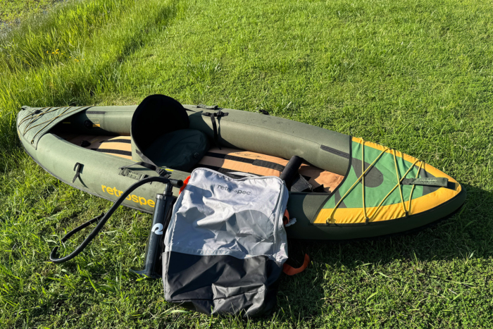 Retrospec Coaster kayak with seat, pump, and carry bag on the grass