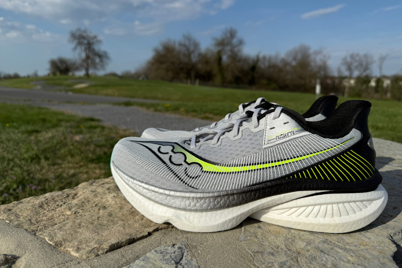 Saucony Endorphin Azura shoe on a stone wall beside a paved path