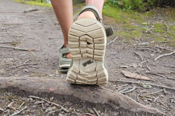 Close up of the Teva sandal outsole showing the tread while stepping over a tree root