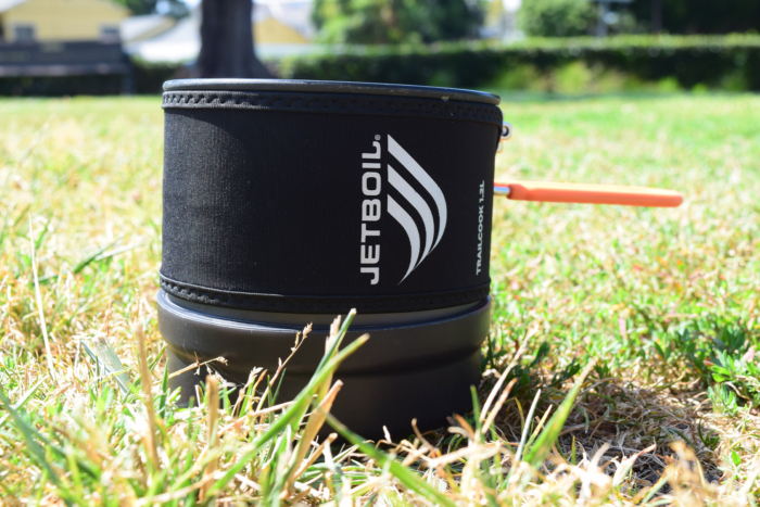 Jetboil TrailCook pot sitting in the grass with its orange handle extended