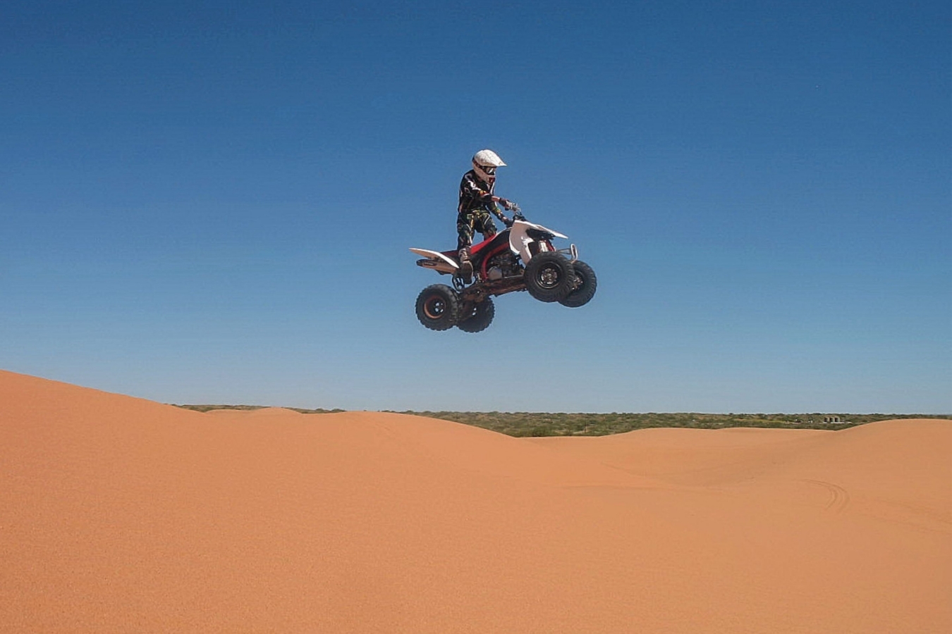 person on a 4x4 jumps by sand dunes