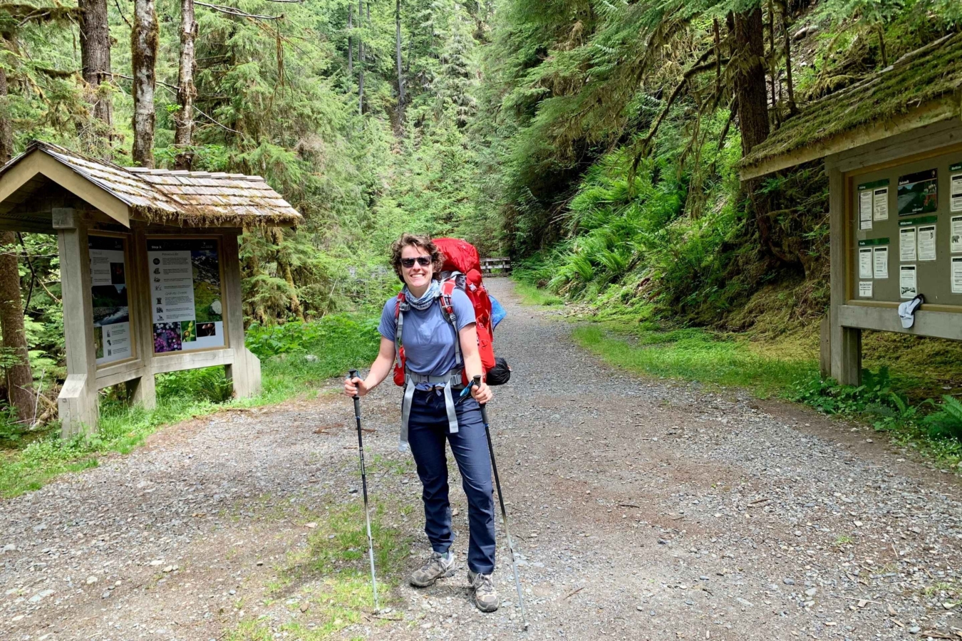 female backpacker stands and smiles