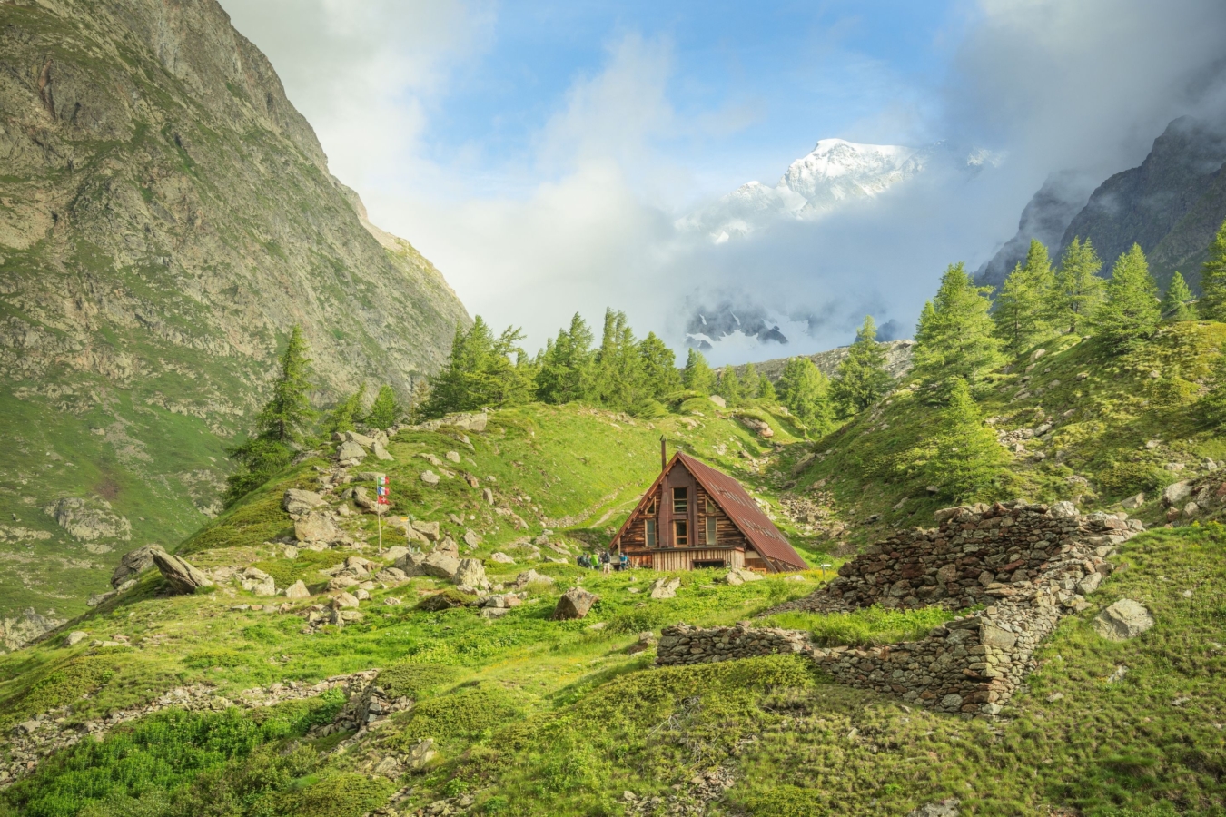 small a-frame hut in green mountain landscape