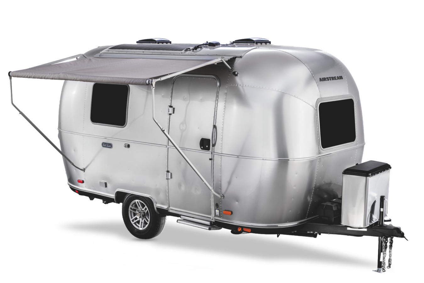 A small aluminum Airstream travel trailer is parked on a white background with its awning deployed.