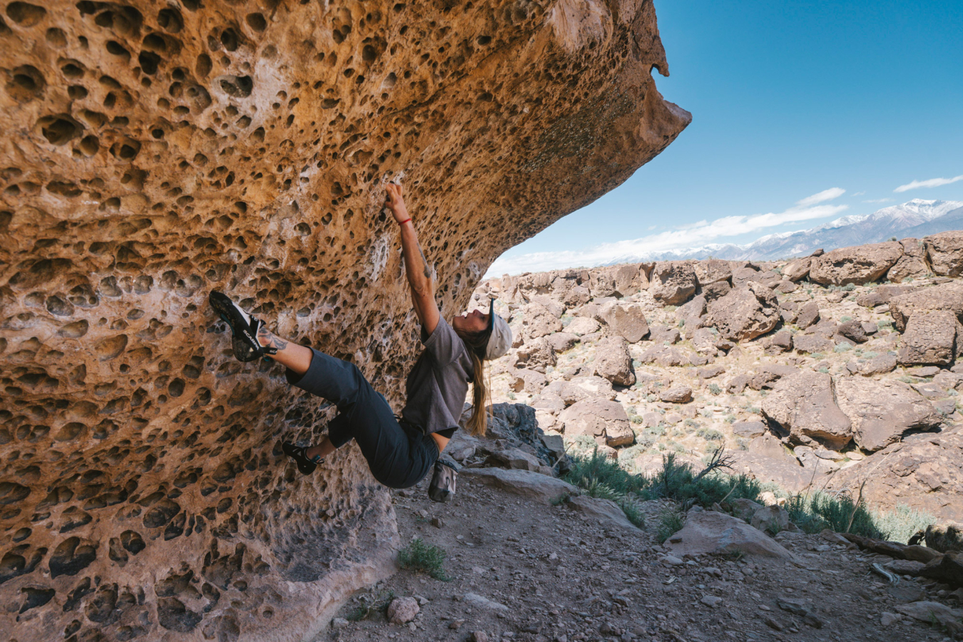 Climber wearing Sequence Pants boulders on a steep desert rock wall