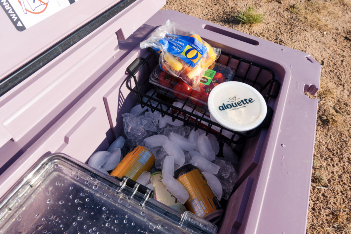 Food basket positioned above drinks and ice inside the rolling cooler
