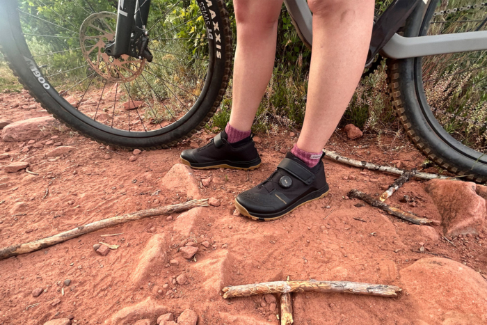 Crankbrothers flat MTB shoes on rocky ground beside a mountain bike