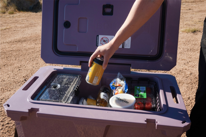 Person reaching into a BrüTank cooler packed with refreshments