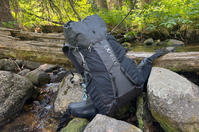 Exped Lightning 50 backpack resting on rocks beside a woodland creek