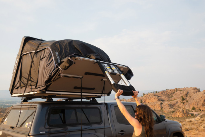 Woman folding the ladder beneath the Skycamp 4.0 Trio rooftop camper