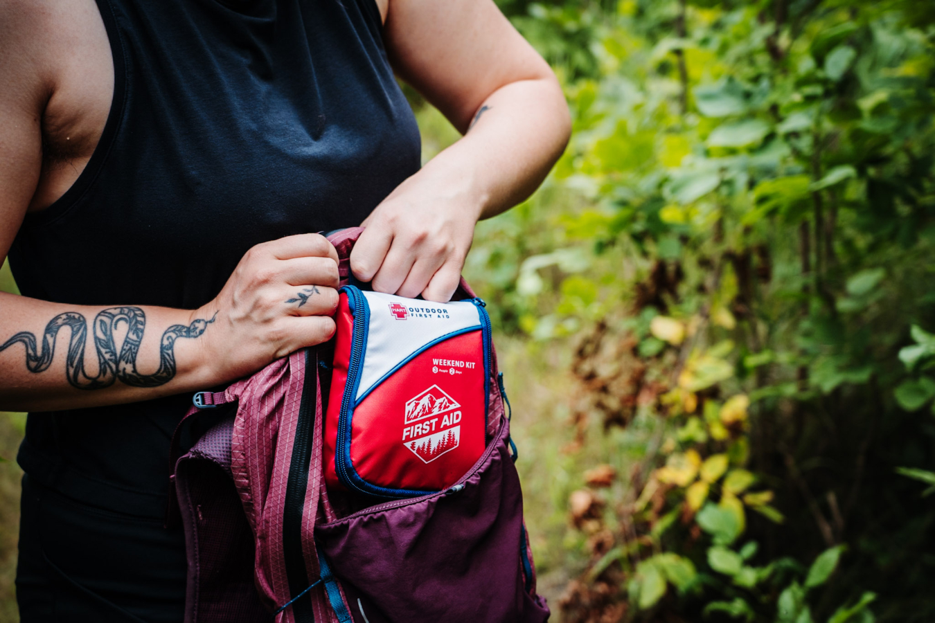 Hiker packing a HART outdoor first aid kit into a backpack