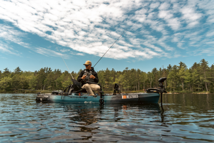 An angler holding a fishing rod and looking in a lake on the Old Town Sportsman 120 Pro