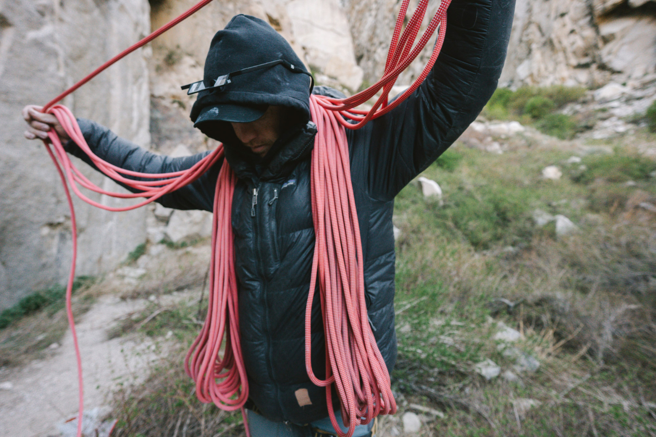 Climber carrying coiled red rope over both shoulders