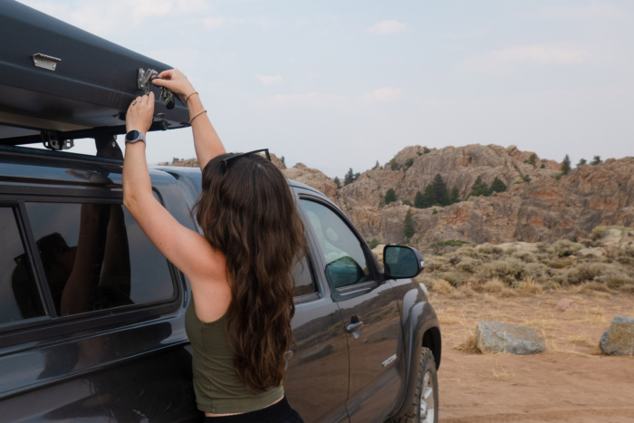 Woman fastening the hard shell of an iKamper rooftop camper