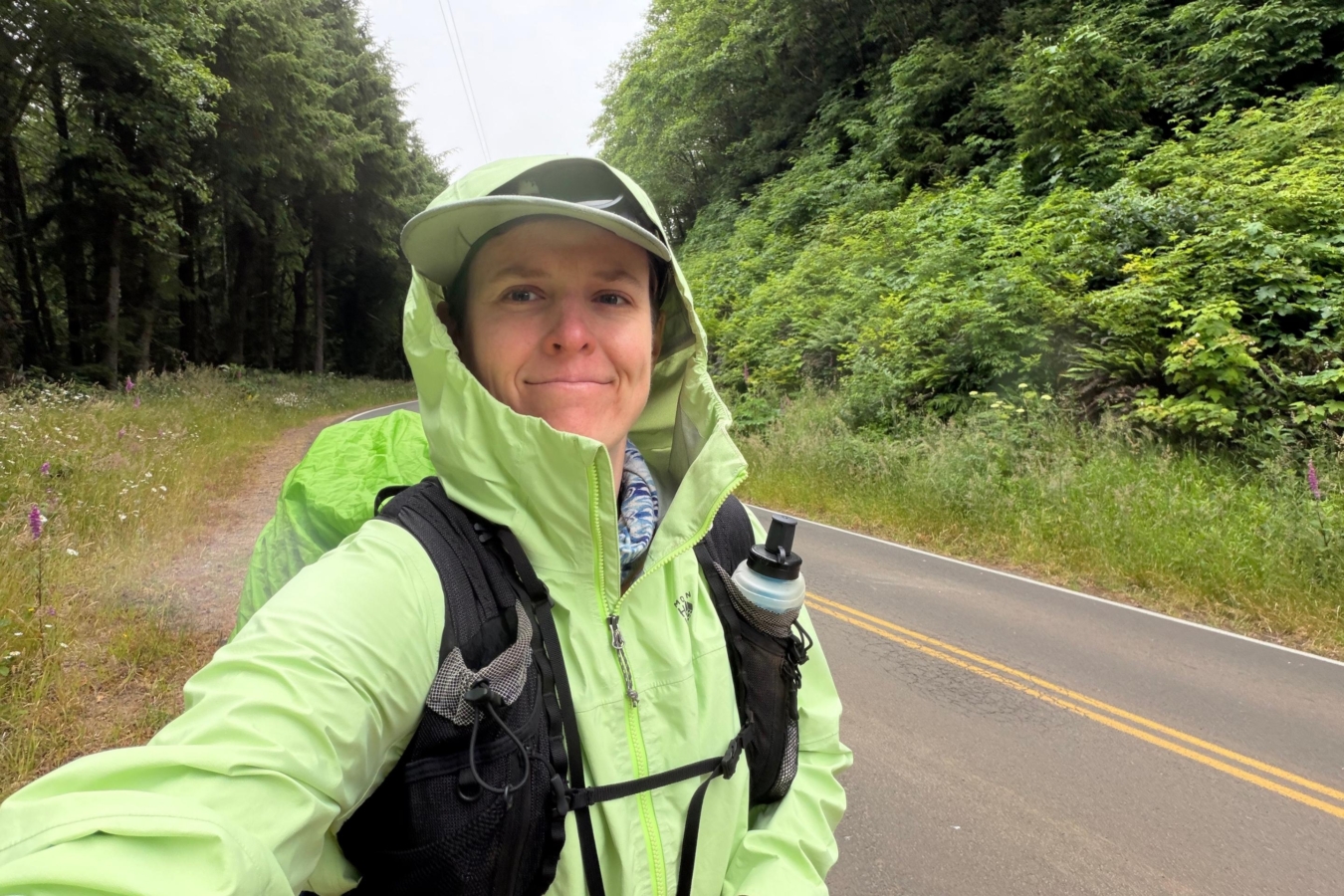 selfie of a person smiling in a green rain jacket