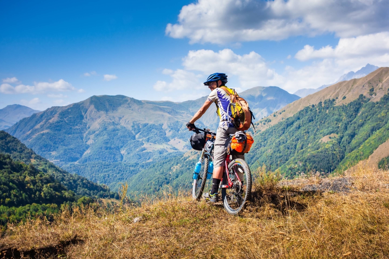 biker stands at viewpoint of mountain