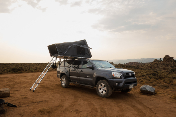Pickup with an open Skycamp rooftop tent in rocky mountain terrain
