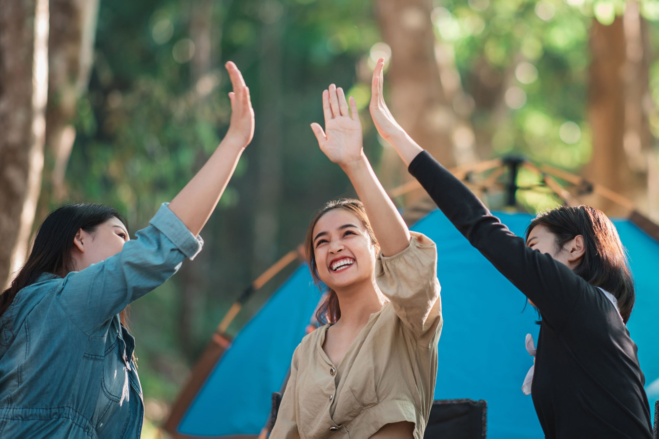 three women high-fiving in front of a tent