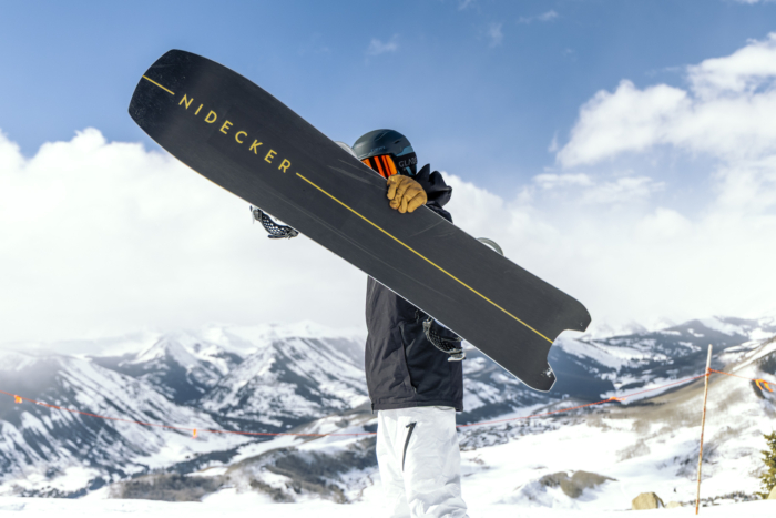 snowboarder holding up board with base facing forward