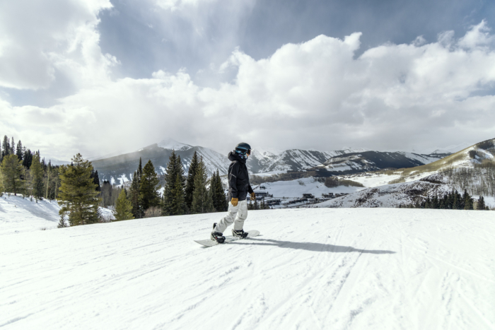 rider descending slope on Merc with mountains in background