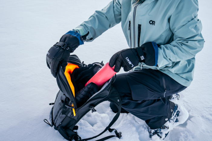 gloved skier hands opening pack with bottle