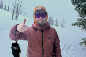 Skier wearing a Mountain Hardwear jacket gives a thumbs-up in snowy conditions