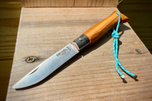 Opinel Néo6 knife open on a wooden surface with a blue cord lanyard