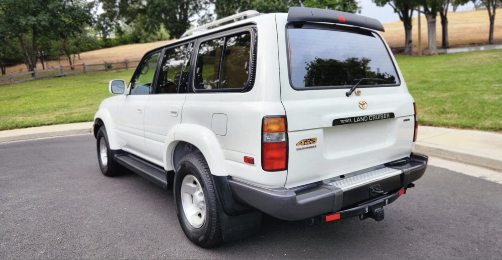 A white 1997 Toyota Land Cruiser is parked in a cul-de-sac