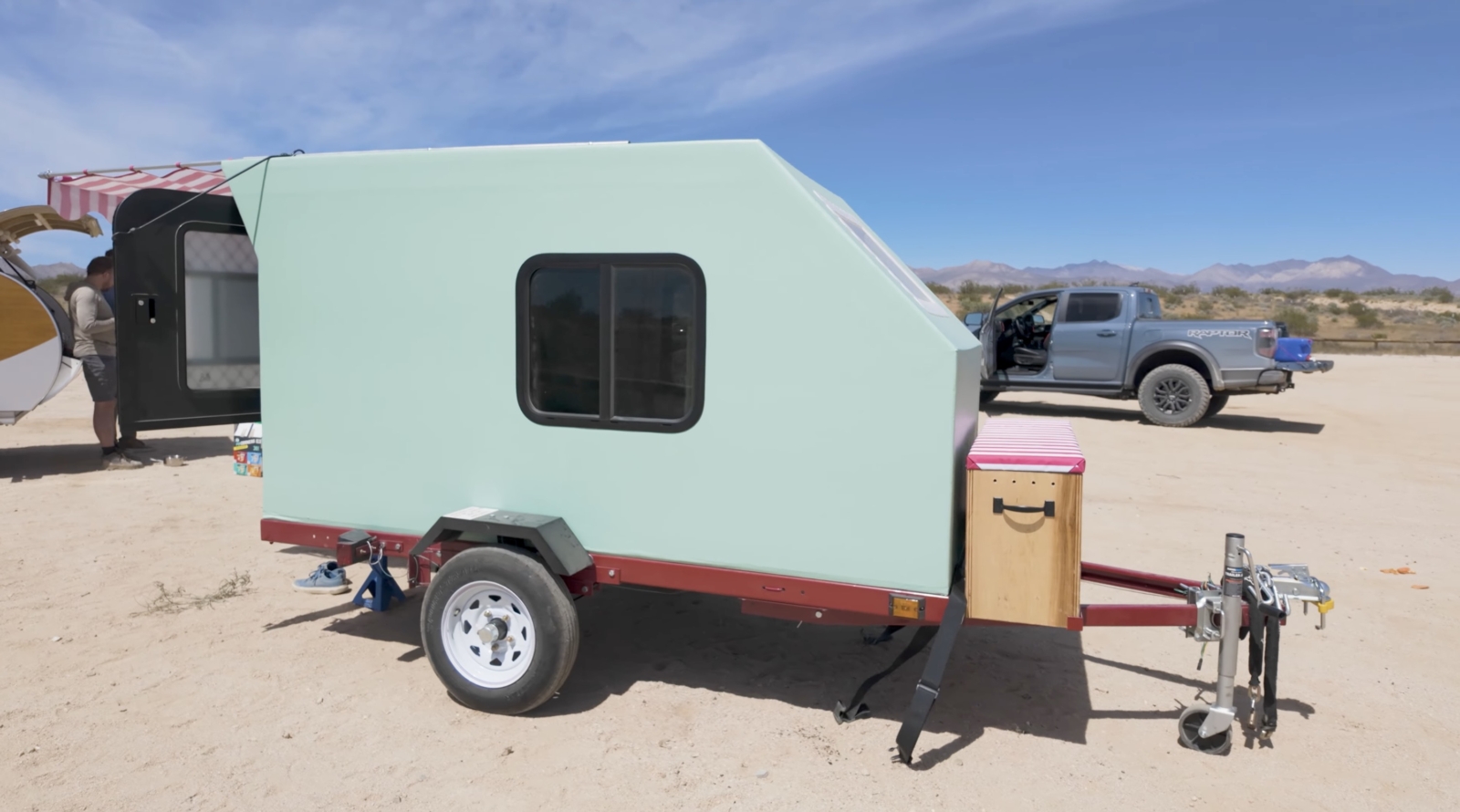 A pale green trailer is parked in the desert