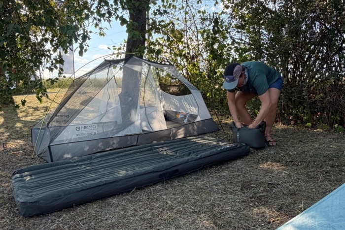 person uses sack to blow up sleeping pad
