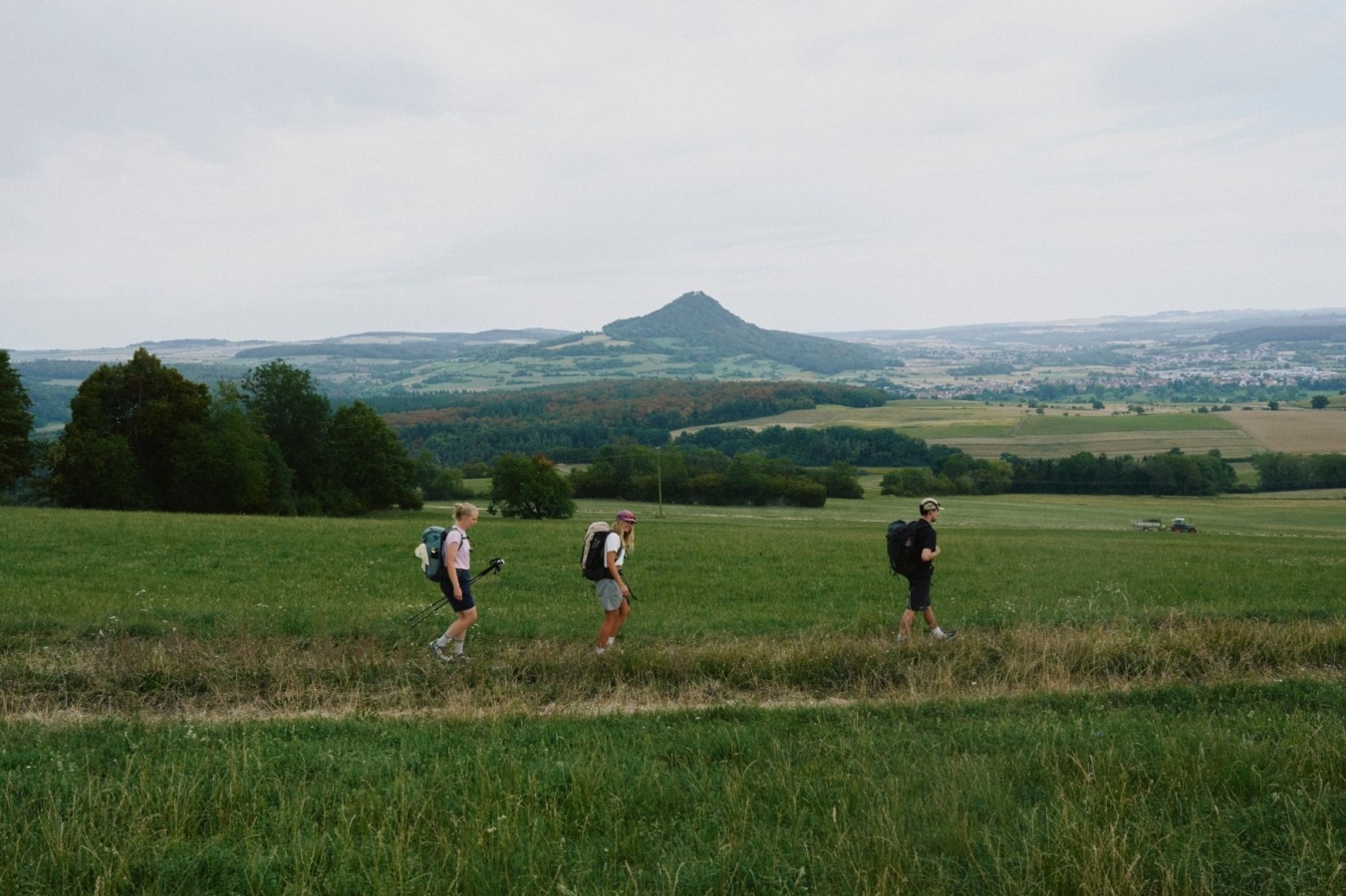 three hikers on trail with mountain background