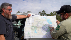 Forest Service ranger pointing to a motor vehicle use map with citizen looking on.